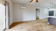 This contemporary 660 square foot apartment offers a thoughtful blend of style and functionality. The heart of the home is an open-concept living area, seamlessly combining the kitchen and living room. The kitchen is a standout feature, boasting dark wood cabinetry, stainless steel appliances, and a large central island with a white quartz countertop, perfect for meal preparation or casual dining.

The living area is bright and airy, with hardwood flooring that extends throughout most of the apartment. Large windows and sliding glass doors in the bedroom provide ample natural light and access to outdoor views. The bedroom, measuring 150 square feet, offers a comfortable retreat with plush carpeting and a ceiling fan for added comfort.

The bathroom is well-appointed with a single vanity, large mirror, and a combination bathtub and shower. Modern fixtures and finishes contribute to the overall contemporary aesthetic. A dedicated closet space with wire shelving provides ample storage options.

Climate control is ensured through both central air conditioning and individual ductless units in the main living area and bedroom. The apartment also features recessed lighting and pendant lights, adding to the modern ambiance. With its efficient layout and high-quality finishes, this apartment offers a perfect blend of comfort and style for urban living.