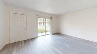 Located at 2035 Kings Hwy in Clearwater, Florida, this single-story, one-bedroom, one-bathroom unit offers a clean and functional layout designed for comfortable everyday living. The open combined living and dining area is the heart of the home, finished with light gray wood-look flooring that extends throughout much of the space. A sliding glass door floods the room with natural light and provides direct views of the surrounding outdoor grounds. The galley-style kitchen runs along a single corridor, featuring white cabinetry, a warm-toned countertop with an integrated sink, a skylight panel overhead, and white appliances including a refrigerator and range. The bedroom is a well-proportioned retreat finished with plush carpet, a window with outdoor greenery views, and generous closet storage provided by two louvered double-door closets. The full bathroom includes a tiled tub-shower combination, a vanity with countertop and mirror, and light flooring that ties the space together. Crisp white walls throughout the unit create a bright, neutral palette that is easy to personalize. The unit's efficient single-floor design ensures a smooth, accessible flow between all rooms.