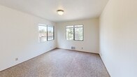 Located at 19914 Military Rd S in SeaTac, Washington, this 2-bedroom, 1-bathroom residence offers a well-organized single-floor layout designed for comfortable everyday living. The living area is bright and welcoming, featuring soft carpeting underfoot and a large picture window that frames lush, tree-lined views while flooding the space with natural light. The kitchen is open and functional, featuring a white peninsula countertop with a built-in sink that connects seamlessly to the living area. Dark cabinetry—both upper and lower—provides ample storage, while a white refrigerator and electric range complete the setup. The primary bedroom is generously sized, offering dual windows with verdant outdoor views and a sliding-door closet that provides practical storage. The second bedroom mirrors a similar layout, with its own window overlooking the trees and carpet flooring. Both bedrooms are bright and neutral in finish. The full bathroom features tile flooring, a single-sink vanity with dark cabinetry, a large mirror, and a tub/shower combo. Hallways connect the rooms efficiently throughout the unit. Overall, the space maintains a clean, neutral palette with white walls and warm wood-toned accents, creating a calm and livable ambiance.