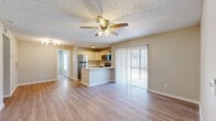 Located at 3024 N Powers Dr in Orlando, FL, this single-story 2-bedroom, 2-bathroom home offers a well-organized layout designed for comfortable everyday living. The open-concept living and kitchen area forms the heart of the home, featuring light wood-style flooring, neutral toned walls, and a ceiling fan overhead. Sliding glass doors with vertical blinds fill the living space with natural light and provide access to the outdoors. The kitchen is equipped with stainless steel appliances — including a refrigerator, electric range, and microwave — complemented by light cabinetry, a light countertop peninsula with an undermount sink, and a textured ceiling throughout. Both bedrooms are generously proportioned, with the primary bedroom offering its own closet and direct access to a private bathroom featuring a tiled tub-shower combo. The second bedroom is bright with a window and ceiling fan, served by a second bathroom with a tiled walk-in shower. Two closets provide ample storage, and a dedicated laundry area adds convenience. Wood-style flooring runs consistently throughout, lending a cohesive and clean aesthetic across the entire home.