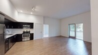 Located at 5548 Hollywood Blvd in Los Angeles, this single-floor unit offers a contemporary design with a clean, modern aesthetic throughout. The open-plan living and kitchen area is anchored by light-toned hardwood-style flooring that extends throughout the main living spaces, creating a cohesive and airy feel. Elevated ceilings contribute to a sense of spaciousness, while recessed and track lighting ensure the interior is well-illuminated.

The kitchen is a standout feature, outfitted with dark espresso cabinetry that reaches the ceiling, white quartz countertops, a white subway tile backsplash, and a full suite of stainless steel appliances including a refrigerator, electric range, over-the-range microwave, and dishwasher. The living area includes access to a private outdoor space through sliding glass doors with window blinds, allowing natural light to filter in.

The bedroom features soft carpeting, a ceiling fan, a closet with sliding doors, and a window with natural light. A dedicated alcove houses a stacked washer and dryer, adding convenience. The bathroom is finished with a dark vanity, white quartz countertop, a large mirror, and a tub/shower combination, all set against light wood-style flooring and crisp white walls.