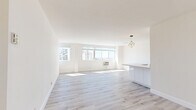 Located at 1746 N Orange Dr in the heart of Hollywood, Los Angeles, this well-appointed one-bedroom, one-bathroom unit offers a bright, modern living experience across a single thoughtfully designed floor. Light wood-tone flooring runs throughout, complementing the clean white walls and creating a cohesive, airy aesthetic.

The open-concept living room and kitchen area is the centerpiece of the unit. The living room is generously proportioned, bathed in natural light from a wide bank of windows that frame sweeping views of the Los Angeles cityscape. The kitchen features sleek, high-gloss white cabinetry extending to the ceiling, quartz countertops, recessed lighting, and a full suite of stainless steel appliances including a refrigerator, range, and built-in microwave. A peninsula provides additional counter space and separation between the kitchen and living areas.

The bedroom is a comfortable, well-lit space with its own large windows offering city views and a dedicated closet. The bathroom is finished in crisp white tones and includes a tub-shower combination with a sliding glass enclosure, a wall-mounted toilet, and a modern vanity with quartz countertop. Every room reflects a clean, contemporary design sensibility suited to urban Los Angeles living.