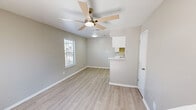 Located in Seabrook, Texas, this two-story residence offers a well-organized layout spread across two floors. The main level houses the living room, dining area, and kitchen, all finished with light wood-look vinyl plank flooring that lends a clean, modern feel. The kitchen is efficiently designed with white cabinetry, light countertops, a single-basin sink, and black appliances including a range, microwave, refrigerator, and dishwasher. A pass-through counter connects the kitchen to the dining and living areas, enhancing the open feel of the floor. Ceiling fans are present throughout, promoting comfortable airflow. Neutral gray walls and abundant natural light from multiple windows create a bright, welcoming ambiance on both levels. A staircase leads to the upper floor, where the generously sized primary bedroom is carpeted for comfort and features a ceiling fan, a walk-in closet, and direct access to the full bathroom. The upper level also includes a private balcony, offering an outdoor retreat. Textured ceilings add a subtle architectural detail throughout the home. The overall design is clean and functional, making efficient use of the available space.