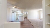 Located on N Indian Springs Dr in Tucson, AZ, this single-story home offers three bedrooms and two bathrooms within a efficiently arranged floor plan. The open-concept living and kitchen area serves as the heart of the home, where wood-look flooring extends through the main living spaces. A tile-surround fireplace anchors the living room, adding a functional focal point, while a ceiling fan provides comfort overhead. A sliding glass door with vertical blinds allows natural light into the living area and provides outdoor access.

The kitchen is positioned adjacent to the living space and features a peninsula with a breakfast bar, light wood cabinetry, white appliances including a refrigerator, electric range with over-the-range microwave, and a skylight that brightens the workspace. Ample upper and lower cabinet storage lines the walls.

The three bedrooms feature neutral carpet flooring and textured ceilings, with windows providing natural light. The primary bedroom is a comfortable size with closet access. Two bathrooms serve the home: one with a shower-only enclosure and wood-look flooring, and a second full bathroom with a tub/shower combination, light wood vanity, and laminate countertop. A connecting hallway links the bedrooms and bathrooms, completing the functional single-floor layout.