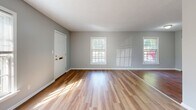 Located at 1139 Minor Ln in Louisville, Kentucky, this single-floor, one-bedroom, one-bathroom home offers a functional and comfortable layout. Throughout the main living areas and bedroom, hardwood-style flooring in warm honey and rich walnut tones creates a cohesive, inviting atmosphere. The living room is a well-proportioned open space bathed in natural light from multiple windows, with neutral gray walls and clean white trim that lend a bright, airy feel. A hallway connects the main rooms, leading to the kitchen and bedroom. The galley-style kitchen is lined with warm wood cabinetry on both sides, offering ample storage and counter space, complemented by light tile flooring and a double-basin sink. The spacious primary bedroom features rich hardwood-style floors, a window for natural light, and the notable convenience of two side-by-side closets, providing generous storage. The bathroom is finished with classic white subway-style wall tile surrounding a full tub-shower combo, a patterned mosaic tile floor, and a white vanity with built-in storage. The overall ambiance throughout the home is clean, neutral, and move-in ready, making efficient use of every room.