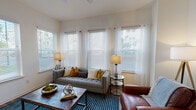 This well-designed single-floor residence offers a thoughtfully planned open-concept layout that seamlessly connects the main living areas. The living room is bathed in natural light from an array of large windows dressed with sheer curtains and wood blinds, creating an airy, welcoming atmosphere. Rich hardwood-style flooring flows throughout the space, adding warmth and continuity.

The kitchen is a standout feature, boasting dark espresso cabinetry, granite countertops, stainless steel appliances, and a generous island with pendant lighting overhead — ideal for both cooking and casual dining. Adjacent to the kitchen, the dining area offers direct access to an exterior door and wall space for décor, making it a functional yet stylish gathering spot.

The bedrooms are comfortable and well-lit, each featuring ceiling fans, hardwood-style flooring, and windows with outdoor views. The primary bedroom connects to an en-suite bathroom showcasing a dual-sink vanity with granite countertops, dark wood cabinetry, a large mirror, and access to a walk-in closet. A secondary bathroom provides a single-sink vanity with matching finishes and a tiled shower, maintaining a consistent design aesthetic throughout.

Overall, the space presents a clean, modern, and cohesive design with neutral tones, quality materials, and an abundance of natural light at every turn.