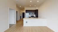 Located on an upper floor at 705 N 1st St in Tacoma, Washington, this modern single-level residence offers a thoughtfully designed layout with clean finishes throughout. The open-concept living and kitchen area serves as the heart of the unit, featuring light wood-style flooring, recessed lighting, and soaring ceilings that enhance the sense of spaciousness. Large windows flood the interior with natural light while framing impressive views of the Tacoma skyline and surrounding waterfront.

The kitchen is well-appointed with dark espresso cabinetry extending to the ceiling for ample storage, stainless steel appliances including a refrigerator, range, and built-in microwave, and a light-toned countertop island with an integrated sink — ideal for both cooking and casual dining.

The bedroom is carpeted for comfort and features a generously sized window that captures expansive outdoor views, including the waterfront and cityscape beyond. A sliding barn-style door adds a contemporary architectural detail to the interior hallway.

The bathroom is finished with wood-style flooring, a full soaking tub and shower combination with a curved curtain rod, a dark-cabinetry vanity with a crisp white countertop, and clean neutral wall tones that contribute to a calm, functional atmosphere throughout.