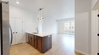 Located at 409 Broadway Dr N in Fargo, ND, this well-appointed 2-bedroom, 2-bathroom residence offers a thoughtfully designed single-floor layout with modern finishes throughout. The open-concept kitchen serves as the heart of the home, featuring a large center island with a built-in sink, white quartz countertops, rich dark-stained cabinetry, white upper cabinets with subway tile backsplash, stainless steel appliances, and stylish pendant lighting. The kitchen flows seamlessly into the living area, which is bathed in natural light from large floor-to-ceiling windows offering elevated views of the Fargo cityscape. Light wood-style flooring extends throughout the main living areas, creating a clean and cohesive aesthetic. The primary bedroom is generously sized, carpeted for comfort, and includes a walk-in closet outfitted with wire shelving systems. The primary bathroom features a long vanity with dark cabinetry, a large mirror, and a bathtub. The second bedroom is also carpeted and benefits from natural light and city views through oversized windows. A second full bathroom includes a tub/shower combo and matching dark wood vanity. A dedicated in-unit laundry room with a full-size washer and dryer adds everyday convenience to this modern urban residence.