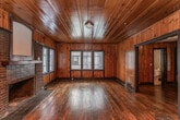 Located at 151 E Blount Ave in Knoxville, TN, this two-floor property blends traditional character with practical updates throughout. The living areas are defined by warm knotty pine wood paneling that extends from the walls to the ceilings, complemented by rich hardwood floors that flow throughout the main level. A standout feature of the living room is a classic brick fireplace, which serves as a natural focal point and adds to the space's historic charm. Multiple windows allow natural light to filter through, enhancing the warmth of the wood-toned interiors.

The kitchen is outfitted with dark wood cabinetry, tile flooring, and a suite of black appliances, including a refrigerator, range, and dishwasher. A wide window above the sink brings in additional daylight. A dedicated laundry area accommodates a full-size washer and dryer, adding everyday convenience.

The bedrooms feature hardwood floors, neutral-toned walls, and closet storage, with windows that provide natural light and outdoor views. The bathrooms are tastefully updated, offering tile surrounds, dark wood vanities, and fixtures that include both a tub/shower combination and a separate walk-in shower with sliding glass doors. A half bath with a granite-topped vanity adds further functionality to the layout.
