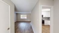 Located on Front Street in Durham, North Carolina, this two-floor residence offers a well-organized layout with a neutral color palette and a blend of practical finishes throughout. The main level features wood-style plank flooring that extends through the open living area and into the entryway, providing a cohesive and clean aesthetic. Natural light enters through a window in the living room, creating a welcoming atmosphere. Adjacent to the living space, the kitchen is outfitted with white shaker-style cabinetry, grey stone-patterned countertops, a mosaic tile backsplash, and stainless steel appliances including a refrigerator, range, and dishwasher. A main-level bathroom includes a white vanity with a light stone countertop and a tub-shower combination with a safety grab bar. A staircase connects the two floors, transitioning to carpeted bedroom spaces on the upper level. The bedrooms offer plush carpet flooring, natural light from windows with blinds, and ample closet space, including mirrored sliding-door closets in the primary bedroom. An additional upper-level bathroom mirrors the clean, white vanity design found on the main floor. Throughout, the space maintains a consistent, understated finish.