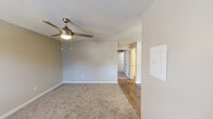 This single-story unit located on Spartacus Drive SW in Huntsville, Alabama, offers a straightforward, functional layout distributed across several distinct areas. The floor plan, visible in the overhead scan, reveals a well-organized arrangement connecting the living space, kitchen, and bedrooms in a compact, efficient design.

The living area is finished with neutral-toned carpet and features a ceiling fan with an integrated light fixture. Textured ceilings are consistent throughout the unit, contributing to a uniform aesthetic. Neutral gray and beige wall tones keep the space feeling open and adaptable.

The galley-style kitchen runs along a narrow corridor and is outfitted with white cabinetry above and below the countertops, a double-basin sink, a white electric range, a refrigerator, and an overhead range hood. A window at the end of the kitchen allows natural light to filter in, brightening the workspace. Wood-look flooring runs through the kitchen and entry areas, providing a durable surface in high-traffic zones.

The bedrooms are carpeted and share the same neutral palette as the rest of the unit. Each room includes a ceiling fan with lighting and has access to closet space. Windows in the bedrooms allow for natural ventilation and daylight. The overall ambiance of the unit is clean, neutral, and move-in ready.