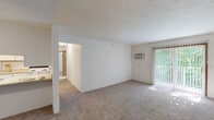 Located at 1721 Bond St in Niles, Michigan, this single-floor, 2-bedroom, 1-bathroom unit offers a functional and well-organized layout. The combined living room and kitchen area forms the heart of the home, with the spacious living room featuring plush carpeting, a textured ceiling, a wall-mounted air conditioning unit, and a sliding glass door that fills the room with natural light and provides access to an outdoor view. A baseboard heating system runs along the wall for efficient warmth throughout. A pass-through counter connects the living area to the galley-style kitchen, which is equipped with white cabinetry trimmed in warm wood accents, a stainless steel sink, laminate countertops, and hardwood-style flooring. Appliances include a refrigerator, electric range, and dishwasher. The primary bedroom is generously sized, featuring a ceiling fan with light fixture, a window overlooking greenery, carpeting, and a dedicated closet outfitted with wire shelving for organized storage. The second bedroom is equally comfortable with carpet flooring and easy hallway access. The full bathroom includes a single-sink vanity with white cabinetry, tile flooring, and a shower/tub combination. A hallway connects all rooms, contributing to a logical and efficient flow throughout the unit.
