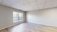 This studio unit at 1701 143rd St W in Burnsville, Minnesota, offers a well-organized single-floor layout that makes efficient use of its compact footprint. The space is finished with light wood-style plank flooring that runs throughout, complemented by neutral gray and beige wall tones that create a clean, modern aesthetic. A drop-panel ceiling with integrated lighting provides a consistent look across the unit.

The combined kitchen and living area serves as the heart of the studio. The kitchen is equipped with gray shaker-style cabinetry, granite-look countertops, a white subway tile backsplash, and a full suite of stainless steel appliances including a refrigerator, range, microwave, and dishwasher. The open living zone flows naturally from the kitchen, benefiting from a large window that invites natural light and provides an outdoor view.

The full bathroom features a soaking tub and shower combination with clean white surround panels, a toilet, and tile flooring. Additional storage is provided by a dedicated closet, while a separate utility room adds practical functionality. The overall ambiance is bright, clean, and move-in ready, offering a straightforward and functional living environment suited for everyday comfort.