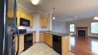 This well-appointed 2-bedroom, 2-bathroom single-floor residence offers a thoughtfully designed layout that balances comfort and functionality. The open-concept kitchen flows seamlessly into the living area, creating an inviting space for daily living and entertaining. The kitchen is equipped with warm honey-toned oak cabinetry, granite countertops, a peninsula with an undermount sink, and a full suite of black appliances including a refrigerator, electric range, over-the-range microwave, and dishwasher. Tile flooring grounds the kitchen, while rich hardwood flooring extends throughout the living area. The living room is anchored by a classic fireplace with a wood-trimmed surround, flanked by windows that bring in natural light, and finished with crown molding and a ceiling fan. Both bedrooms are carpeted and feature crown molding and ceiling fans, with the primary bedroom offering a walk-in closet. The two bathrooms are identically appointed with granite-topped oak vanities, tile flooring, and tub-shower combinations with sliding glass enclosures. A dedicated in-unit laundry room with a full-size washer and dryer adds everyday convenience to this comfortable, move-in-ready residence.