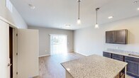 Located at 1055 Simon Crestway in Waunakee, WI, this thoughtfully designed one-bedroom, one-bathroom unit offers a smart and efficient single-floor layout. The open-concept living and kitchen area serves as the heart of the home, anchored by a generous granite-topped island illuminated by elegant pendant lighting. The kitchen is well-appointed with dark wood cabinetry, granite countertops, stainless steel appliances including a refrigerator, range, and microwave, and a undermount sink. Warm hardwood-style flooring flows throughout the main living areas, complementing the neutral gray tones of the walls. The living area is bright and welcoming, featuring a sliding glass door dressed with vertical blinds that allows natural light to pour in. The bedroom offers plush carpeting, a ceiling fan, a sun-filled window with outdoor views, and closet access for added storage. Two closets provide practical organization throughout the unit. The bathroom is finished with a granite-topped vanity, a large mirror, and a walk-in shower. Clean lines, modern finishes, and a cohesive neutral palette give this unit a fresh, move-in-ready feel throughout.