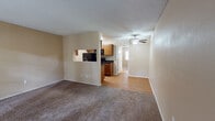 Located at 5441 N Swan Rd in Tucson, Arizona, this single-floor unit offers a practical and comfortable layout designed for everyday living. The living area is generously sized, finished with wall-to-wall carpet and neutral beige walls that create a warm, inviting atmosphere. A textured ceiling runs throughout, and a ceiling fan with light fixture provides both comfort and illumination in the central living space. Natural light filters in through a glass-paneled front door, adding brightness to the open floor plan.

The kitchen is connected to the living area via a convenient pass-through window, offering an open feel while maintaining defined spaces. It features warm honey-toned wood cabinetry, dark granite-style countertops, and wood-look laminate flooring. Black appliances, including a range, microwave, and refrigerator, provide a cohesive and modern contrast to the cabinetry.

The bedroom is a quiet, carpeted retreat with a window fitted with blinds, allowing for adjustable natural light. The full bathroom includes a full-size soaking tub with a tiled surround in earthy tones, complemented by wood-look flooring and matching wood cabinetry for storage. The overall design is clean, functional, and well-suited for comfortable residential living in the Tucson area.