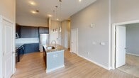 Located at 2120 N Brevard St in Charlotte, NC, this well-appointed apartment offers a thoughtfully designed single-floor layout with two bedrooms and two full bathrooms. The kitchen serves as a central highlight, featuring dark espresso cabinetry extending to the ceiling, granite countertops, a subway tile backsplash, stainless steel appliances, and a kitchen island with pendant lighting and an undermount sink — all complemented by light hardwood-style flooring that flows throughout the main living areas. The soaring ceilings in the kitchen and living area lend an open, airy feel to the space. Both bedrooms are generously proportioned, finished with soft neutral carpet, light gray walls, and windows with blinds that bring in natural light. The spacious primary bedroom includes an adjoining closet. Each bathroom is finished consistently with granite-topped dark vanities, undermount sinks, tile surround tub/shower combinations, and light wood-style tile flooring. One bathroom features an elongated vanity with ample storage and a dedicated shower, while the second offers a full tub. The overall design reflects a clean, modern aesthetic with a cohesive neutral palette throughout.