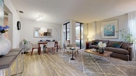 This single-floor residence is designed with an open-concept layout that seamlessly connects the living, dining, and kitchen areas, creating a cohesive and functional living environment. Light wood-style flooring flows throughout the main living spaces, complementing the neutral gray and white color palette that lends the home a clean, contemporary aesthetic.

The living room is generously proportioned, anchored by large floor-to-ceiling windows and a sliding glass door that flood the space with natural light and provide views of the surrounding greenery. The dining area sits adjacent to the living room, benefiting from the same natural light, and offers enough space for a full dining table and additional furnishings.

The kitchen features white shaker-style cabinetry, granite-look countertops, and stainless steel appliances including a refrigerator, dishwasher, and range, providing a practical and attractive cooking space.

Two bedrooms are present, each carpeted and well-sized. The primary bedroom includes a sliding glass door with outdoor views, while a second bedroom offers a quieter retreat. The bathroom is finished with white cabinetry, a single vanity with stone-look countertops, and wood-style flooring. A textured ceiling is consistent throughout the residence.