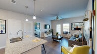 Located at 16201 Biltmore Ave in Pflugerville, TX, this one-bedroom, one-bathroom residence offers a thoughtfully designed open-concept layout that maximizes every square foot. Wood-style flooring flows throughout the main living areas, creating a cohesive and contemporary feel.

The kitchen serves as the heart of the home, anchored by a granite-topped island with bar seating and elegant pendant lighting overhead. Dark espresso cabinetry provides ample storage and contrasts beautifully with the light countertops. Stainless steel appliances — including a refrigerator, range, and microwave — complete the well-equipped space. The kitchen opens seamlessly into the living area, which features a ceiling fan, large windows, and access to an outdoor balcony, allowing natural light to fill the room.

The generously sized bedroom accommodates a full suite of furnishings with ease. It includes multiple windows for natural light, a ceiling fan, and a louvered closet door offering convenient storage access.

The bathroom is functional and clean, featuring a tub/shower combination with white tile surround, dark cabinetry for storage, and granite countertops that echo the kitchen's finishes.

Overall, this residence delivers a modern, practical living environment with consistent finishes and a bright, open atmosphere throughout.