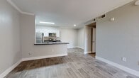 This single-floor residence offers a clean, contemporary design highlighted by wood-look luxury vinyl plank flooring that flows consistently throughout the entire space. The open-concept layout seamlessly connects the living area to the kitchen, creating a bright and functional environment bathed in neutral gray tones and crisp white trim.

The kitchen is well-equipped with a full suite of stainless steel appliances, including a refrigerator, electric range, over-the-range microwave, and dishwasher. White shaker-style cabinetry pairs with dark countertops to create a stylish contrast, while the peninsula provides additional prep space and a natural divider between the kitchen and living area.

The living room is generously sized, featuring crown molding, a ceiling fan, and sliding glass doors fitted with vertical blinds that open to an outdoor patio, allowing natural light to fill the space.

The bedroom is a comfortable retreat, complete with its own ceiling fan, a sliding glass door to the patio, and access to a spacious walk-in closet with built-in shelving. The bathroom features a tub-shower combination, a vanity with dark countertop and white cabinetry, and wood-look flooring. A standout convenience is the in-unit laundry closet, accessible directly from the bathroom, housing a stacked washer and dryer.