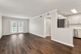 This single-floor residence offers 4 bedrooms and 2 full bathrooms within a thoughtfully designed layout. The combined kitchen and living room serves as the heart of the home, where rich, dark hardwood-style flooring flows throughout the main living areas. The living room is bright and open, featuring crown molding, a textured ceiling, and French doors that lead to an outdoor balcony, allowing natural light to fill the space. The kitchen is well-equipped with gray shaker-style cabinetry, crisp white countertops, a subway tile backsplash, stainless steel appliances including a dishwasher and range, and a peninsula that provides additional prep space. A central hallway connects the bedrooms, which feature plush carpeting and windows with blinds offering views of the surrounding area. The primary bedroom includes a dedicated closet for ample storage. Both bathrooms are finished consistently with gray vanity cabinetry, white countertops, brushed nickel hardware, tile surround tub-shower combinations, and warm hardwood-style flooring. Two additional closets provide practical storage throughout. The neutral color palette and clean finishes create a cohesive, move-in-ready aesthetic throughout the entire residence.