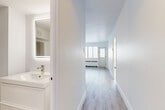 Located at 1030 Rue Cherrier in Montréal's vibrant Plateau-Mont-Royal neighbourhood, this one-bedroom, one-bathroom unit offers a clean, modern aesthetic throughout. Light wood-tone laminate flooring runs continuously across all rooms, creating a cohesive and airy feel. Crisp white walls and trim further enhance the bright, fresh atmosphere.

The kitchen is well-appointed with white shaker-style cabinetry extending to the ceiling for generous storage, light stone-look countertops, a tiled backsplash, and a full suite of stainless steel appliances including a refrigerator, electric range, and dishwasher.

The bedroom is a comfortable size, featuring a wide multi-pane window that fills the room with natural light, baseboard heating, and a built-in mirrored sliding-door closet that adds both function and depth to the space.

The bathroom is thoughtfully designed with a backlit LED vanity mirror, a modern white floating vanity, and a separate toilet and bathtub area with wood-look tile flooring. A second vanity area off the hallway provides added convenience.

A hallway with an additional closet connects the rooms efficiently, and the layout flows naturally from entry to living areas. The unit's clean, renovated finishes make it a polished and functional urban residence.