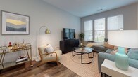 Located at 2614 Smooth Alder St in Gambrills, Maryland, this single-floor residence offers a thoughtfully designed layout with contemporary finishes throughout. The living area serves as the heart of the home, featuring warm hardwood-style flooring, soft neutral walls, and an array of large windows dressed with white blinds that flood the space with abundant natural light and offer pleasant outdoor views. The open layout provides a comfortable and inviting atmosphere ideal for both relaxing and entertaining.

The kitchen is outfitted with stainless steel appliances, including a range, over-the-range microwave, and refrigerator, complemented by light wood cabinetry, white quartz-style countertops, and a subtle tile backsplash. Under-cabinet lighting adds a refined touch to this well-appointed cooking space.

The bedroom is a serene retreat, appointed with plush carpeting, soft gray walls, and windows that welcome natural light. It connects to a generously sized walk-in closet featuring wire shelving and hanging rods for ample storage.

The bathroom presents a clean, modern aesthetic with a floating wood-toned vanity, a wide white countertop, an undermount sink, and a large mirror accented by bright vanity lighting. Neutral tile flooring and crisp gray walls round out the polished design, creating a cohesive and comfortable living experience throughout the home.
