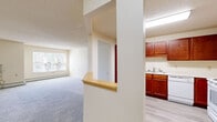 Located at 2408 W Broadway Ave in Minneapolis, MN, this second-floor unit offers a well-organized, single-level layout with two bedrooms and one bathroom. The open-concept living area features soft carpet flooring, neutral wall tones, and a textured ceiling, creating a clean and comfortable atmosphere. Natural light filters in through windows, enhancing the bright and airy feel of the space.

The kitchen is a standout feature, boasting rich cherry-toned cabinetry that extends to the upper walls, light countertops, and a full suite of white appliances including a range, dishwasher, and refrigerator. Light wood-look vinyl flooring grounds the kitchen, which opens to the living area via a convenient pass-through counter.

Both bedrooms are carpeted and feature wall-mounted HVAC units, baseboard heating, and windows that bring in natural light. The spacious primary bedroom offers ample room for furnishings. The unit includes four closets in total, one of which is a generously sized walk-in with wire shelving—providing excellent storage throughout.

The bathroom features a walk-in shower with a grab bar and clean white finishes. A hallway connects the main rooms, contributing to the unit's efficient and functional flow.