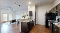 Located at 5900 Charles Merle Dr in Austin, TX, this one-bedroom, one-bathroom residence offers a well-designed, single-floor layout that makes efficient use of its space. Rich hardwood-style flooring runs throughout, providing a warm and cohesive aesthetic across every room.

The open-concept kitchen and living area serve as the heart of the home. The kitchen features dark espresso cabinetry, granite countertops, a peninsula with a sink that doubles as a breakfast bar, and black appliances including a refrigerator, range, and dishwasher. Track lighting overhead adds a modern touch. The adjacent living room benefits from large windows and a glass-panel door that invite natural light, complemented by a ceiling fan for year-round comfort.

The bedroom is a well-proportioned retreat with elevated ceilings, a ceiling fan, a wide window with outdoor views, and a double-door closet offering ample storage. Its calm, neutral palette creates a restful atmosphere.

The bathroom continues the home's consistent design language with dark cabinetry, a granite-topped vanity, a large mirror, a walk-in shower, and a separate soaking tub, all set against bright white walls and hardwood-style flooring. The overall ambiance throughout the residence is clean, modern, and inviting.