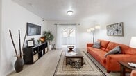 This single-story home in Riverton, Utah offers a well-organized layout across three bedrooms, three bathrooms, and a dedicated office. The open-concept dining, kitchen, and living area forms the heart of the home. The living room features carpeted flooring and neutral walls, creating a bright, comfortable gathering space. The adjacent dining area is finished with stone-look tile flooring and connects seamlessly to the galley-style kitchen, which is lined with light wood cabinetry on both sides, ample counter space, white appliances, and matching tile flooring—providing a functional and efficient workspace. The dedicated office includes a window with natural light and carpeted flooring, offering a quiet, versatile area suitable for work or study. The bedrooms are carpeted and well-proportioned, with windows allowing natural light. The primary bedroom includes a walk-in closet with built-in shelving. The three bathrooms feature stone-look tile flooring and light wood vanities; one includes a full tub-shower combination. A utility room rounds out the interior. The overall aesthetic is clean and neutral throughout.