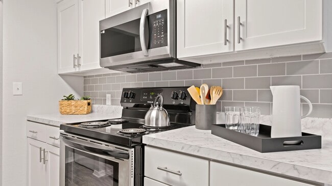 Indulge in culinary luxury with our renovated kitchens, featuring a sophisticated stainless steel appliance package including stove, fridge, microwave, and dishwasher. - The Avenue