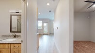 This well-designed one-bedroom, one-bathroom unit offers an efficient and functional single-floor layout. Light wood-tone flooring flows throughout the open-concept living and kitchen areas, creating a bright and cohesive aesthetic. The kitchen is equipped with a full suite of stainless steel appliances — including a side-by-side refrigerator with ice and water dispenser, an electric range, built-in microwave, and dishwasher — complemented by light wood cabinetry, granite-style countertops, and a tile backsplash. Recessed lighting illuminates the space from above. The living area opens directly to an exterior door flanked by windows fitted with horizontal blinds, allowing natural light to filter in while maintaining privacy. The bedroom features soft carpeting, a ceiling fan with light fixture, a window with outdoor views, and a sliding-door closet. The bathroom includes a walk-in glass-enclosed shower with large-format tile surround and brushed metal fixtures. Throughout the unit, neutral wall tones, clean white trim, and consistent finishes contribute to a modern, move-in-ready ambiance suited for comfortable everyday living.