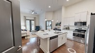 Located at 455 W Sullivan St in Kingsport, Tennessee, this well-appointed 2-bedroom, 1-bathroom residence offers a thoughtfully designed single-level floor plan. The open-concept kitchen and living area serves as the heart of the home, showcasing soaring ceilings, rich hardwood-style flooring, and abundant recessed lighting. The kitchen is outfitted with crisp white shaker cabinetry, light stone countertops, stainless steel appliances including a refrigerator with ice maker, and a large center island with an integrated sink, dishwasher, and bar seating for multiple guests. Pendant lights hang above the island, adding a refined touch. The living room features a ceiling fan, large French doors that invite natural light and provide outdoor access, and generous wall space. The primary bedroom offers soaring ceilings, a dedicated closet, and a bright window with outdoor views. The second bedroom is equally comfortable, with a large window overlooking greenery. The bathroom includes a glass-enclosed walk-in shower and wood-look flooring. Two closets provide practical storage throughout. The unit also includes an in-unit laundry area. With its clean, neutral palette and modern design details, this residence offers a polished and functional living environment.