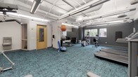 This well-appointed fitness center at 3924 Excelsior Blvd in St. Louis Park, Minnesota offers a comprehensive exercise facility designed to support a wide range of workout routines. The space is spread across a single floor and is characterized by its open, airy layout with notable ceiling height, exposed ductwork, and bright linear lighting that gives the room a clean, modern industrial aesthetic.

The flooring throughout is a distinctive teal-patterned carpet tile, adding a pop of color to the otherwise neutral gray and white palette of the walls and ceiling. Natural light filters in through multiple windows along the perimeter, providing views of the surrounding neighborhood and keeping the space feeling fresh and energized.

The cardio zone is well-equipped with multiple treadmills, an elliptical trainer, and a recumbent stationary bike, each featuring individual media screens for an engaging workout experience. A dedicated strength and functional training area includes a cable machine, a full dumbbell rack, stability balls, a BOSU trainer, step platforms, and a medicine ball, catering to a variety of fitness levels and training styles. A large wall-mounted mirror enhances the sense of space while allowing users to monitor their form. The facility is thoughtfully organized, spacious, and fully equipped to serve as a primary fitness destination.