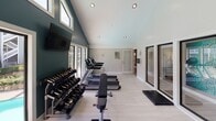 Located at 8625 Winter Oaks Ln in Charlotte, NC, this well-appointed fitness center is thoughtfully designed to support a full range of workout routines. The space features soaring vaulted ceilings that rise dramatically along a bold teal accent wall, creating an open and energizing atmosphere. Light hardwood-style flooring runs throughout, complementing the bright, airy feel cultivated by an abundance of natural light streaming through large floor-to-ceiling windows and elevated clerestory windows.

The cardio zone is equipped with multiple treadmills and an elliptical trainer, all positioned to offer views of the adjacent outdoor pool area through expansive glass panels. A large wall-mounted flat-screen television accompanies the cardio section, providing entertainment during workouts. The strength training area features a professional-grade multi-functional cable machine, a full rack of dumbbells spanning a wide weight range, a weight bench, and exercise mats for floor work. Recessed lighting supplements the natural light throughout the day.

Large sliding glass doors connect the fitness center directly to the adjacent interior space, enhancing accessibility and ventilation. The clean, modern design aesthetic, combined with a comprehensive selection of equipment, makes this fitness center a highly functional and motivating environment for residents.