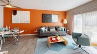 This single-floor unit offers a thoughtfully arranged open-concept layout that seamlessly integrates the sleeping and living areas into one cohesive space. The main area is anchored by a bold accent wall painted in a vibrant orange, adding a striking visual focal point that energizes the room. Wide wood-look plank flooring runs throughout, providing a warm and cohesive foundation across all areas.

Large sliding glass doors open to a private balcony, allowing an abundance of natural light to flood the living space and offering outdoor access. A secondary window further enhances the brightness of the room.

A built-in sliding-door closet provides convenient in-unit storage within the main living area. The galley-style kitchen is efficiently designed with ample white cabinetry, dark countertops, stainless steel appliances, and a functional layout that maximizes workspace.

The bathroom features a long vanity with dark countertops, cream cabinetry with gold-toned hardware, a large mirror, and soft sage-green walls that create a calm, spa-like atmosphere. Wood-look flooring continues into the bathroom, maintaining design continuity throughout the unit.

Overall, the space balances modern finishes with colorful, energetic design choices, resulting in a bright and inviting single-floor unit.
