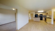 This single-floor, two-bedroom, one-bathroom residence offers a thoughtfully designed open layout that maximizes both functionality and comfort. The living area flows seamlessly into the kitchen, creating a connected, spacious feel throughout the main living space. Light wood-style flooring runs through the primary areas, lending a clean and modern aesthetic, while carpeted bedrooms provide a warm contrast underfoot.

The kitchen is well-appointed with light wood cabinetry, dark countertops, and black appliances including a refrigerator, range, and microwave — all arranged around a peninsula that provides additional prep and seating space. The open sightlines from the kitchen into the living area make the space feel bright and airy.

The two bedrooms are accessed from the main living area and offer private retreats with carpeted floors and closet access. The layout is efficient and practical, with interior doors providing separation between the living spaces and private areas.

With neutral wall tones throughout, light-toned finishes, and a functional floor plan, this residence is well-suited for a variety of living arrangements. The clean, move-in-ready presentation and cohesive design make it an informative and accessible choice for those seeking a well-organized two-bedroom home.
