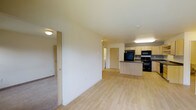 This single-floor, two-bedroom, one-bathroom residence offers a thoughtfully designed open layout that maximizes both functionality and comfort. The living area flows seamlessly into the kitchen, creating a connected, spacious feel throughout the main living space. Light wood-style flooring runs through the primary areas, lending a clean and modern aesthetic, while carpeted bedrooms provide a warm contrast underfoot.

The kitchen is well-appointed with light wood cabinetry, dark countertops, and black appliances including a refrigerator, range, and microwave — all arranged around a peninsula that provides additional prep and seating space. The open sightlines from the kitchen into the living area make the space feel bright and airy.

The two bedrooms are accessed from the main living area and offer private retreats with carpeted floors and closet access. The layout is efficient and practical, with interior doors providing separation between the living spaces and private areas.

With neutral wall tones throughout, light-toned finishes, and a functional floor plan, this residence is well-suited for a variety of living arrangements. The clean, move-in-ready presentation and cohesive design make it an informative and accessible choice for those seeking a well-organized two-bedroom home.