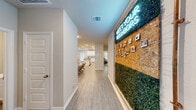 Located at 27035 Beacon Glen Drive in Katy, TX, this single-story home is part of the Villas at Sunterra, an ONM Living rental community. The layout is thoughtfully designed to balance living, working, and private spaces across a generously sized floor plan.

The entrance hallway makes a striking first impression, featuring a decorative living moss and cork board wall accented by a neon "Meet Your Neighbors" sign, setting a welcoming community-oriented tone. Light wood-look flooring flows consistently throughout the home, complementing the neutral, light-gray walls and white trim.

The open-concept kitchen and living area form the heart of the home. The kitchen features white cabinetry, granite countertops, a subway tile backsplash, and a breakfast bar with seating. A dining area with natural light from a rear door sits adjacent. The living room offers comfortable proportions, recessed lighting, a ceiling fan, and a window for natural light.

The primary bedroom includes double doors leading to an en-suite bathroom with a glass-enclosed shower and extended vanity. A second full bathroom features a subway tile tub-shower combo. Two dedicated office spaces provide functional work areas with natural light. The overall ambiance is clean, modern, and purposefully designed.
