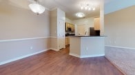 This single-floor residence at 11720 Ravensclaw Ln in Fredericksburg, Virginia, offers a well-organized layout with a practical blend of materials and finishes throughout. The open-concept living and dining area is anchored by warm wood-style flooring, crown molding, and a pendant light fixture above the dining space. A peninsula with dark granite-style countertops connects the kitchen to the main living area, providing both functionality and visual separation. The kitchen features light maple cabinetry, dark countertops, stainless steel appliances including a refrigerator and range, and a built-in microwave, with a corridor-style configuration that maximizes storage and counter space. A door off the kitchen leads to an additional utility area.

The bedrooms are finished with neutral-toned carpet and receive ample natural light through windows dressed with horizontal blinds, offering views of the surrounding landscaped grounds. The bathrooms feature wood-style flooring, a soaking tub with tiled surround, and light vanity cabinetry. Throughout the residence, neutral wall tones and clean white trim contribute to a bright, cohesive ambiance that complements the straightforward and functional design.