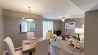 This single-story residence offers a well-organized layout that connects the primary living spaces for a cohesive and functional flow. The living room provides a comfortable gathering space finished with plush carpeting, a ceiling fan, and a sliding glass door that allows natural light to fill the room. Adjacent to the living area, the dining space accommodates a full-sized table and is illuminated by a pendant light fixture, with a pass-through window linking it directly to the kitchen.

The kitchen is efficiently designed with dark cabinetry, granite-style countertops, wood-look flooring, black appliances including a range and dishwasher, and multiple windows that bring in natural light. A door in the kitchen provides additional exterior access.

The bedroom is generously sized, featuring soft carpet, a ceiling fan with light, large windows offering outdoor views, and ample space for a full furniture arrangement. The bathroom is thoughtfully laid out with dark cabinetry, a granite-style vanity countertop, wood-look flooring, and a separate water closet area, providing a practical and organized design.

Throughout the residence, a neutral warm-gray color palette, consistent flooring materials, and ceiling fans in key rooms contribute to a cohesive and comfortable atmosphere.