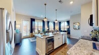 Located at 1550 Kenny Rd in Columbus, Ohio, this thoughtfully designed single-floor residence combines modern elegance with functional living. The open-concept layout connects the kitchen, dining, and living areas seamlessly, creating an inviting, airy atmosphere filled with natural light from striking arched windows draped in rich navy curtains.

The kitchen is a standout feature, showcasing a large central island with granite countertops, white shaker cabinetry, stainless steel appliances, a built-in beverage cooler, and brass pendant lighting that adds a warm, sophisticated touch. The living area flows naturally from the kitchen, benefiting from abundant light and direct access to an outdoor balcony through glass-paneled doors.

The bedrooms are calm and comfortable retreats, each featuring arched windows with outdoor views, plush carpeting, and neutral wall paneling that lends a refined character to the space.

The bathrooms are elegantly finished with patterned hexagonal tile flooring, deep navy subway tile accents, granite-topped vanities, glass-enclosed walk-in showers, and matte black fixtures. A hallway entry with rich hardwood flooring and recessed lighting leads throughout the residence, tying together the cohesive and polished aesthetic of this well-crafted home.