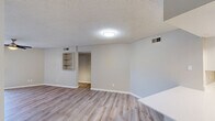 Located at 1440 S Val Vista Dr in Mesa, AZ, this single-floor, three-bedroom, two-bathroom home offers a practical and well-maintained layout. The open-concept kitchen and living area serves as the heart of the home, featuring crisp white cabinetry, a bright white countertop peninsula, stainless steel appliances including a refrigerator, range, and microwave, and light wood-look flooring. A window above the sink brings in natural light, enhancing the clean, modern aesthetic. The living area extends naturally from the kitchen, with light wood-look flooring, a ceiling fan, and a sliding glass door fitted with vertical blinds that opens to an outdoor view. The primary bedroom is generously sized, finished with plush carpet, a ceiling fan, and its own sliding glass door with outdoor views. The additional bedrooms also feature carpet flooring, ceiling fans, and sliding glass doors, with one room including built-in wall shelving for added storage. Two closets provide ample storage throughout. The two bathrooms are finished with white vanities, light wood-look flooring, and clean fixtures — one with a walk-in shower and the other with a tub-shower combo and a window for natural ventilation. Textured ceilings are consistent throughout the home, contributing to its classic character.