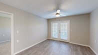 Located at 6721 Lackman Rd in Shawnee, Kansas, this well-appointed 2-bedroom, 2-bathroom residence offers a practical and comfortable single-floor layout. The living room is a bright, open space highlighted by wood-look luxury vinyl flooring, neutral warm-gray walls, a ceiling fan with light, and classic French doors fitted with blinds that invite natural light and provide outdoor access. The kitchen flows seamlessly from the living area and features white shaker-style cabinetry, a dark granite-style countertop with a breakfast bar overhang, stainless steel appliances including a microwave, and recessed lighting overhead. The primary bedroom is a generous retreat with plush carpeting, a ceiling fan, and doors leading to both a dedicated closet and a private en-suite bathroom. The second bedroom also features carpet flooring and a large window that fills the room with natural light. Both bathrooms are finished with white vanity cabinetry, dark countertops, and well-lit vanity mirrors. A dedicated laundry room houses a full-size front-loading washer and dryer set beneath upper white storage cabinets, adding everyday convenience. Throughout the space, consistent neutral tones and clean finishes create a cohesive, move-in-ready atmosphere.