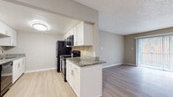 Located at 11301 N 53rd St in Temple Terrace, Florida, this single-floor residence offers a thoughtfully updated interior with a cohesive, modern aesthetic throughout. The kitchen is a standout feature, showcasing white cabinetry with contemporary hardware, granite countertops, a stone tile backsplash, and black stainless steel appliances including a refrigerator, range, and microwave. The kitchen flows seamlessly into the adjacent living and dining areas, creating an open and connected layout. Light wood-style flooring runs throughout the main living spaces and bedrooms, lending warmth and continuity to the interior. The living room is generously proportioned and benefits from a large sliding glass door fitted with vertical blinds, allowing ample natural light and providing access to an outdoor view. The bedrooms are well-sized with neutral wall tones and feature sliding door closets with built-in rods for organized storage. The bathroom is cleanly appointed with a granite-topped vanity, a framed mirror, white cabinetry, and a tub-shower combination with tiled surround. A dedicated in-unit laundry area houses a full-size washer and dryer. Textured ceilings and consistent neutral-toned walls create a calm, move-in-ready atmosphere throughout the entire space.