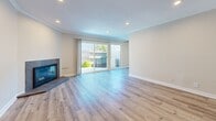 Located in Newport Beach, California, this two-story, 4-bedroom, 3-bathroom home offers a thoughtfully designed layout spread across two floors. The main level features a bright and open living room with wood-look flooring, crown molding, recessed lighting, and a classic fireplace. Large sliding glass doors invite natural light and provide direct access to the private patio, which includes a fenced yard with landscaped mulch beds. The kitchen is outfitted with white shaker cabinetry, dark countertops, a stainless steel dishwasher, and hardwood-style flooring, complemented by a pantry and a dedicated laundry area nearby. A dining room and hallways complete the first floor. Upstairs, four bedrooms feature plush carpeting, neutral tones, and ample natural light from well-placed windows with blinds. The generously sized primary bedroom includes its own closet, while six total closets throughout the home ensure abundant storage. The three bathrooms are finished in clean, white surrounds with brushed nickel fixtures, including walk-in shower stalls. Two staircases with wooden railings connect the floors. The home's warm, neutral palette and functional layout make it a practical and comfortable residence in a desirable Newport Beach location.