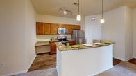 Located at 13625 Haven Ridge Ln. in Charlotte, NC, this single-story residence offers a thoughtfully designed layout with comfortable living spaces throughout. The kitchen is a standout feature, equipped with stainless steel appliances including a refrigerator, electric range, and microwave, complemented by rich wood cabinetry, granite countertops, wood-look flooring, and a breakfast bar with pendant lighting overhead. A dedicated built-in desk area adds functional workspace to the kitchen. The living and dining areas are finished with plush carpeting, crown molding, and ceiling fans, with an elegant arched doorway and large windows that invite generous natural light. A hallway connects the main living areas to the bedrooms, each of which features carpet flooring, a ceiling fan, and windows offering pleasant outdoor views of the surrounding greenery. The primary bathroom offers a dual-sink vanity with wood cabinetry and a large mirror, while the secondary bathroom includes a single-sink vanity and a walk-in shower with glass enclosure. Warm neutral tones and consistent finishes throughout the space contribute to a cohesive and inviting atmosphere.