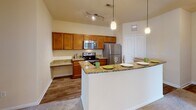 Located at 13625 Haven Ridge Ln. in Charlotte, NC, this single-story residence offers a thoughtfully designed layout with comfortable living spaces throughout. The kitchen is a standout feature, equipped with stainless steel appliances including a refrigerator, electric range, and microwave, complemented by rich wood cabinetry, granite countertops, wood-look flooring, and a breakfast bar with pendant lighting overhead. A dedicated built-in desk area adds functional workspace to the kitchen. The living and dining areas are finished with plush carpeting, crown molding, and ceiling fans, with an elegant arched doorway and large windows that invite generous natural light. A hallway connects the main living areas to the bedrooms, each of which features carpet flooring, a ceiling fan, and windows offering pleasant outdoor views of the surrounding greenery. The primary bathroom offers a dual-sink vanity with wood cabinetry and a large mirror, while the secondary bathroom includes a single-sink vanity and a walk-in shower with glass enclosure. Warm neutral tones and consistent finishes throughout the space contribute to a cohesive and inviting atmosphere.