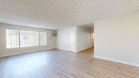 Located at 20909 Parthenia St in Los Angeles, CA, this 2-bedroom, 2-bathroom unit offers a practical and well-appointed single-floor layout. The open living room is a standout feature, showcasing light wood-style laminate flooring, neutral-toned walls, a textured ceiling, and a large picture window with vertical blinds that fills the space with natural light. A wall-mounted air conditioning unit provides climate control directly in the living area.

The kitchen is thoughtfully designed with crisp white shaker cabinets, gray countertops, and a full suite of black appliances including a refrigerator, gas range, microwave, and dishwasher. Ample upper and lower cabinetry, along with a built-in shelving nook, provide generous storage options. The kitchen connects seamlessly to the living area through an open layout.

Both bedrooms are carpeted in a neutral beige tone and feature textured ceilings, soft wall colors, and windows with blinds for natural light and privacy. The primary bedroom offers a comfortable, well-proportioned footprint.

The two bathrooms are clean and functional, each featuring wood-style flooring, white cabinetry with gray countertops, and a window for natural ventilation. One bathroom includes a full soaking tub with tiled surround. A hallway connects the private areas of the unit, completing this efficient and move-in-ready floor plan.