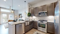 This single-floor residence showcases a thoughtfully designed open layout with contemporary finishes throughout. The gourmet kitchen serves as a central highlight, featuring rich dark-toned cabinetry, a classic white subway tile backsplash, and light granite countertops. A stainless steel farmhouse sink anchors the space alongside a full suite of stainless steel appliances, including a gas range, built-in microwave, dishwasher, and French door refrigerator. Pendant lighting adds a refined touch over the generous kitchen island, which offers comfortable bar seating and flows naturally into the living area.

The living space is bright and welcoming, with recessed lighting, a ceiling fan, and large windows that allow ample natural light. A walk-in closet is conveniently accessible from the main living area. Multiple bedrooms provide comfortable retreats, each appointed with light-toned wood flooring, large windows with urban or garden views, and soft neutral wall tones.

The bathrooms echo the kitchen's design language with matching dark cabinetry, granite vanity tops, large mirrors, and tile flooring, delivering a cohesive and polished aesthetic throughout the entire residence.